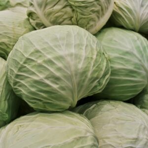 Close-up view of fresh green cabbages piled at a market, emphasizing texture and freshness.