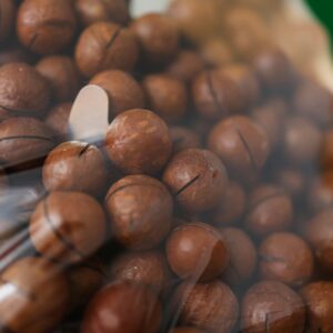 A detailed view of raw macadamia nuts inside transparent packaging, showcasing their natural texture and appeal.