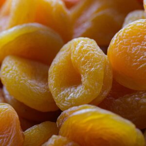 Vivid close-up image of fresh and raw dried apricots on a wooden surface, capturing their vibrant color and texture.
