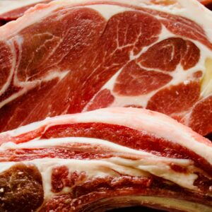 Detailed close-up of raw lamb chops highlighting intricate marbling and rich color.